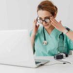 Woman in scrubs using ad-hoc reports for monitoring mid-study
