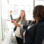 Two people planning a study on a dry erase board