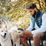 Man using ePRO app on phone while outside with his dog