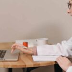 Woman in white code looking at audit trail on laptop