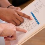 People pointing at numbers on clinical study invoice document