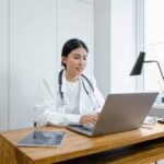 Woman in white coat using laptop for eClinical mid-study updates