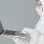 Person in personal protective gear utilizing edit checks while entering data into laptop