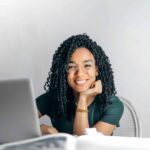 Woman smiling over laptop screen.